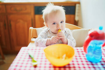 Baby eet Ellas kitchen met lepel in de mond
