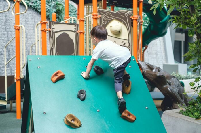 Peuter klimt op klimrek in binnenspeeltuin