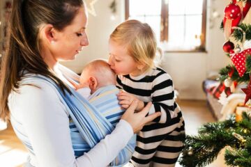 Meisje geeft baby kusje tijdens kerst met corona