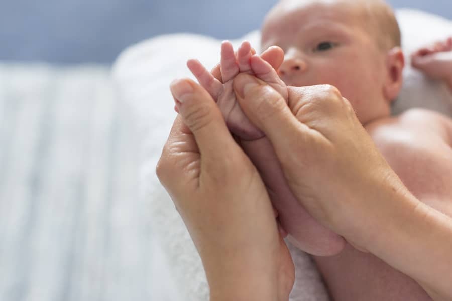 Kraamverzorgende masseert pasgeboren baby