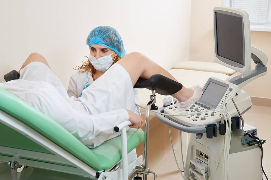 Vrouw ligt in gynaecologische stoel bij fertiliteitsarts voor terugplaatsing embryo