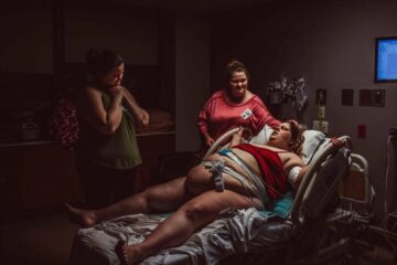 Vrouw tijdens bevalling omringd door vrienden