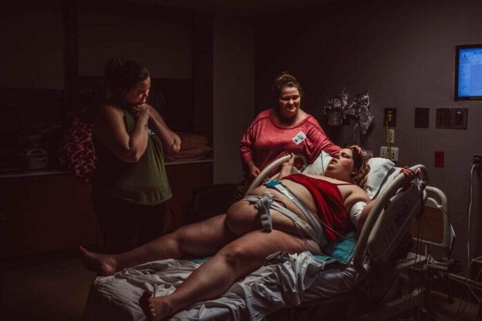 Vrouw tijdens bevalling omringd door vrienden