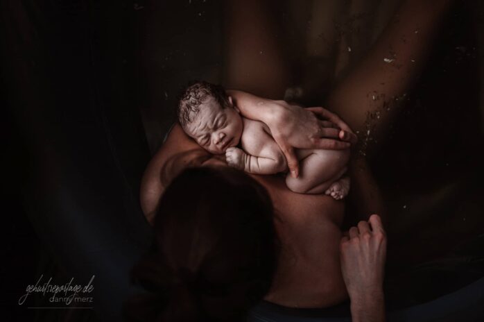 Pasgeboren baby ligt op borst van moeder