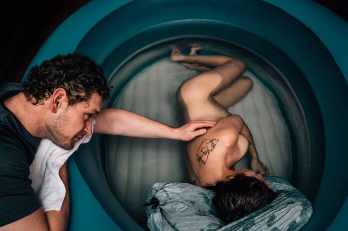 Man ondersteunt vrouw tijdens badbevalling
