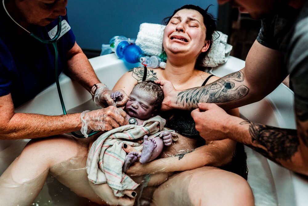 Huilende vrouw met pasgeboren baby in armen