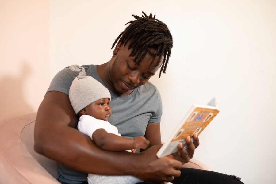 Vader leest tijdens het bedritueel een boekje voor aan zijn baby