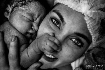 Pasgeboren baby houdt neus van moeder vast
