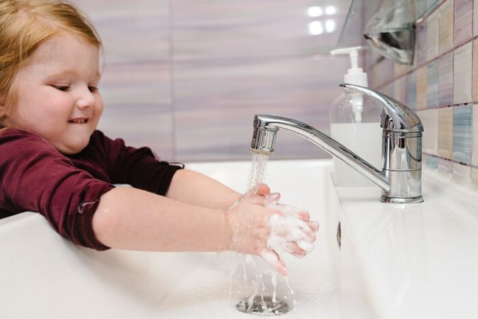 Kind met aarsmaden wast handen