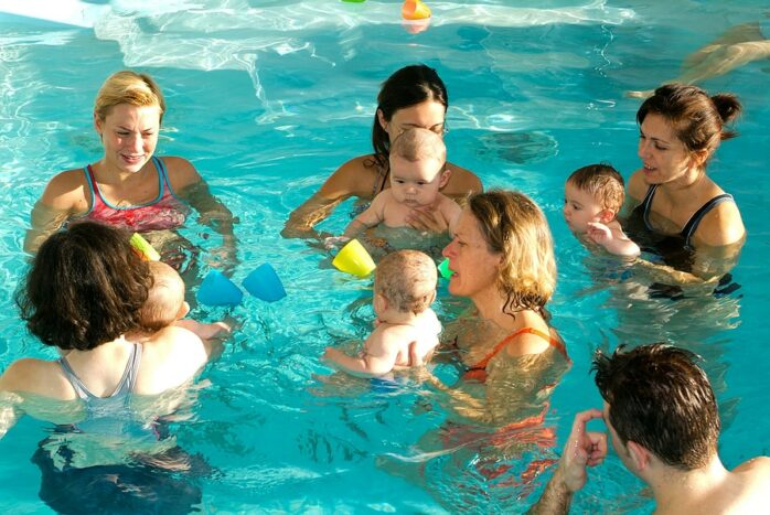 Ouders spelen babyspelletjes in het water met baby tijdens babyzwemmen