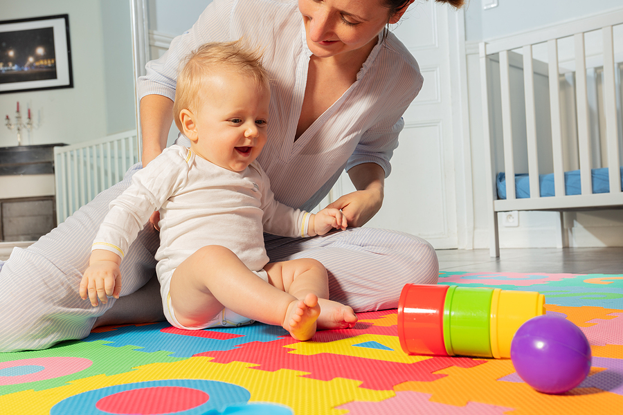Baby 23 Wochen spielt mit Mutter auf Spielteppich