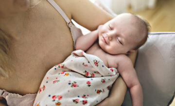 Wochenbett: Mutter hält schlafendes Baby im Arm.