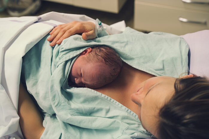 Neugeborenes Baby entspannt sich nach der Geburt auf der Brust der Mama.