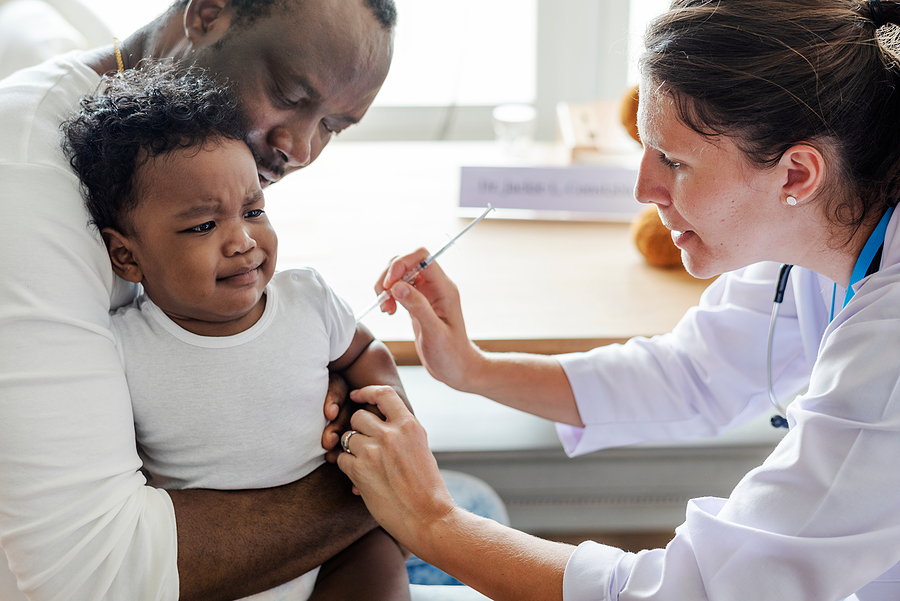 Ein Baby ist bei seinem Papa auf dem Arm und bekommt die von der STIKO empfohlene Impfung.