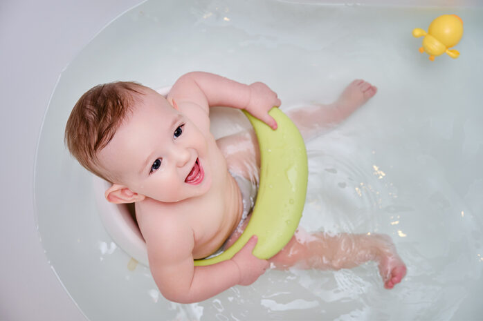Baby sitzt in einem Babysitz in der Badewanne