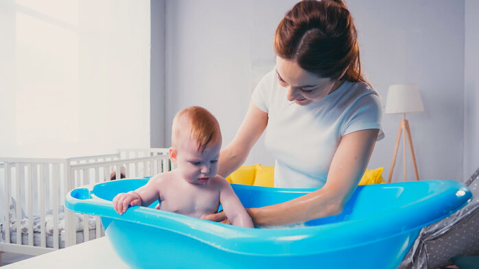 Baby in Badybadewanne wird von Mutter gestützt