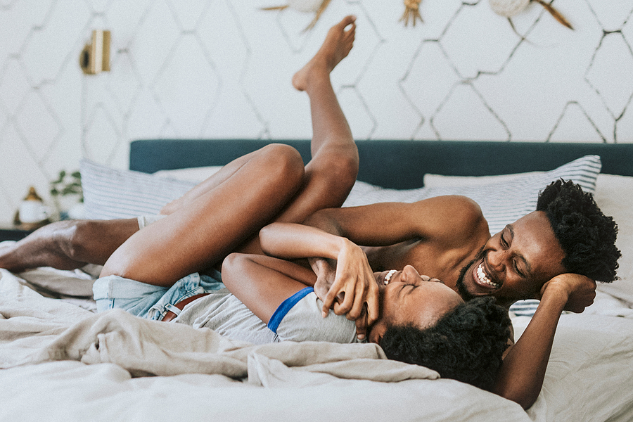 Glückliches Paar liegt zusammen im Bett und lacht