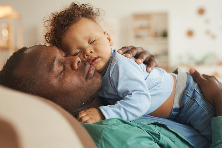 Papa-Blogger macht ein Nickerchen auf dem Sofa mit seinem Baby.