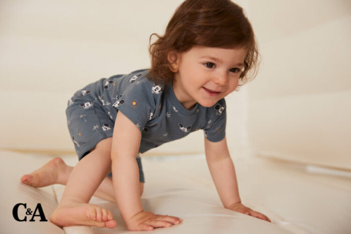 Baby krabbelt in trendiger Babykleidung.