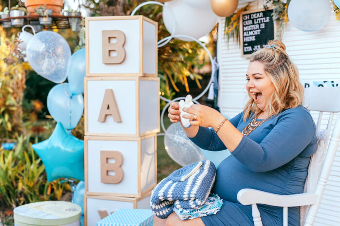 Werdende Mama packt Geschenke bei ihrer Babyparty aus.