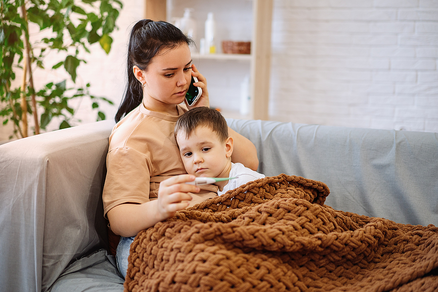 Kind mit spastischer Bronchitis sitzt mit Mama auf dem Sofa.