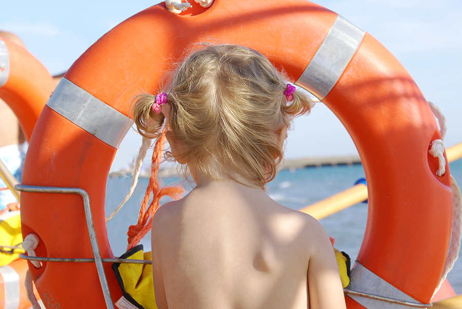 Ertrinken: Kleines Mädchen schaut durch einen Rettungsring aufs Meer.
