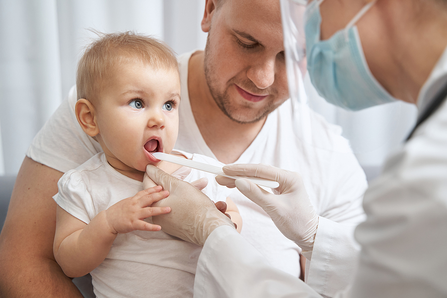 Scharlach: Kinderarzt kontrolliert die rote Zunge eines Babys.