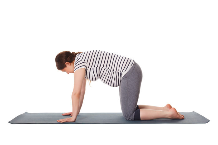 Schwangerschaftsyoga: Schwangere Frau macht die Katze/Kuh Übung auf ihrer Yogamatte